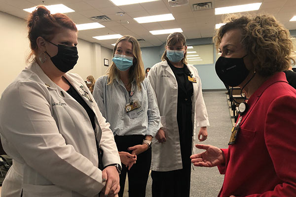 3 nursing students wearing masks talk with Dean Pam Jeffries, also wearing a mask