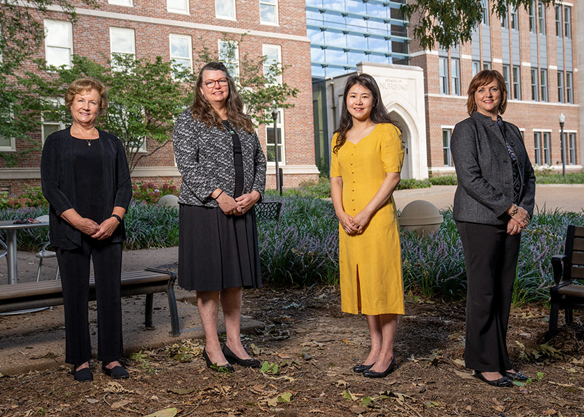 4 professors stand in front of Vanderbilt School of Nursing. All 4 are acute and chronic illness researchers.