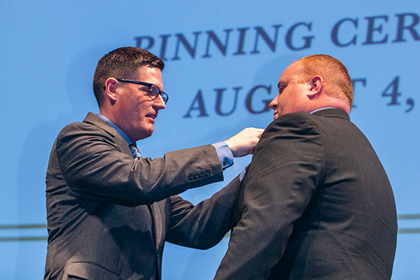 Professor Brian Widmar pins student Daniel Ford