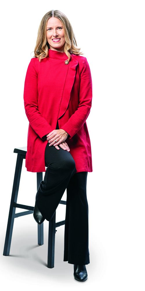 Terrah Akard in red tunic jacket and black trousers, seated on a black stool.