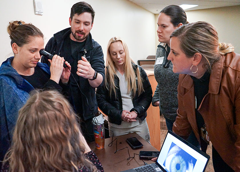 Male sim lab instructor guides SANE students in using equipment for exams