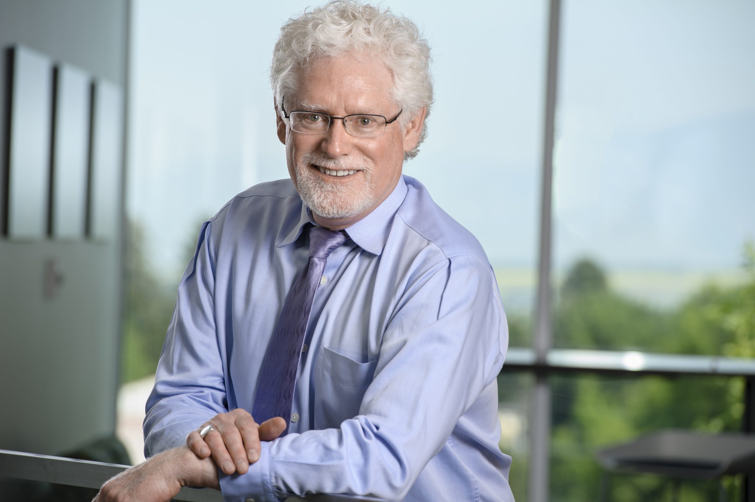 person in blue shirt and blue tie leaning and smiling