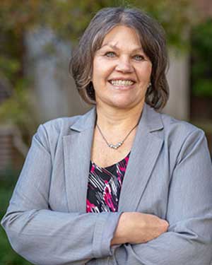 Brenda Kulhanek in a gray blazer and print blouse stands outdoors