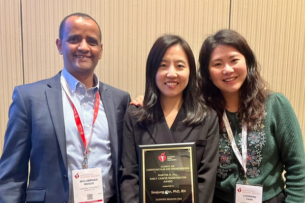 three people smiling, holding an award