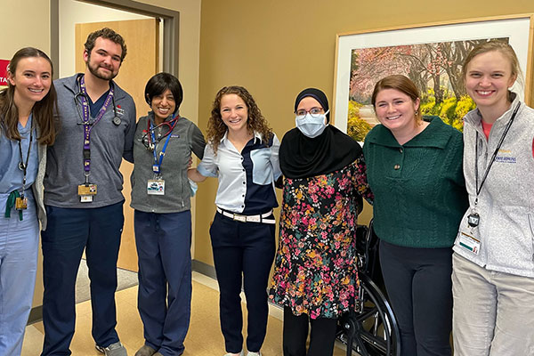 Seven people pose in a row. One man, six women.