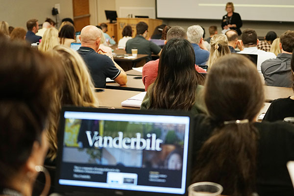 A School of Nursing classroom photographed from the back of the classroom. Students fill seats. In the foreground, a student has his or her laptop open to the Vanderbilt website.