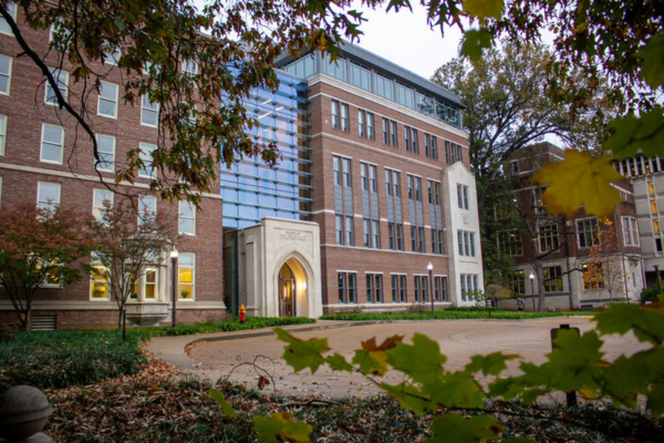 Exterior of brick school of nursing building with driveway in front and fall leaves on the ground