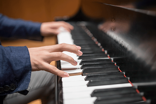 Hands above a black and white piano keyboard