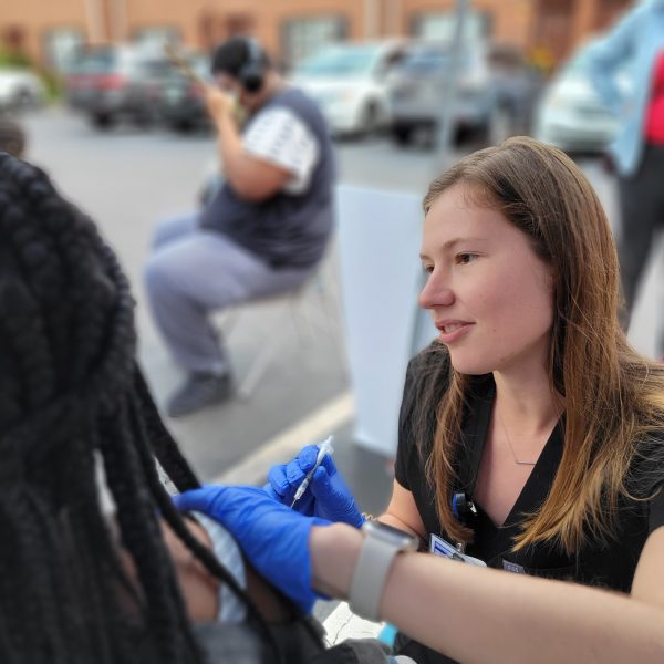 A woman giving a shot to another woman.