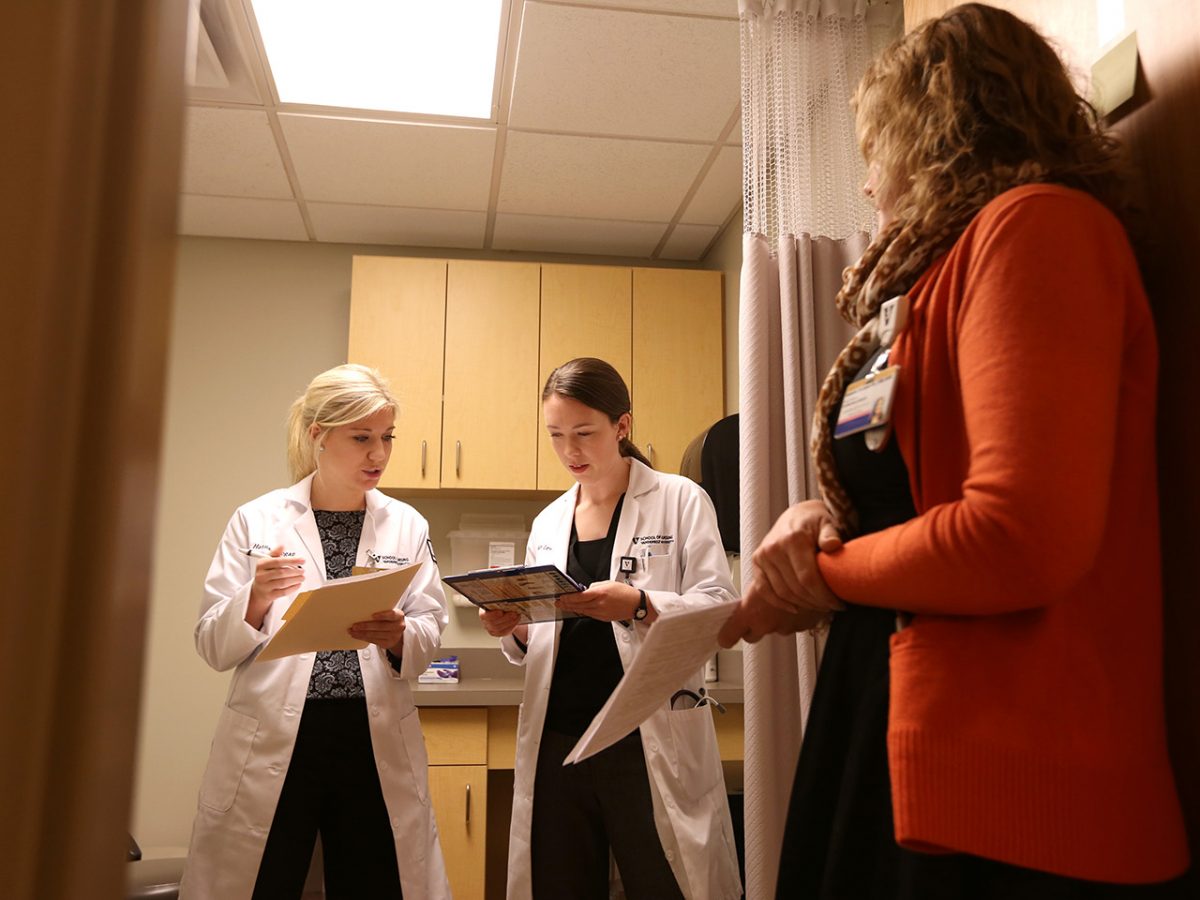 Two nurse-midwifery students look at files, while a Certified Nurse Midwife listens to their diagnosis