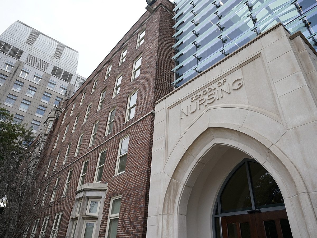 Front of brick, limestone and glass building. The writing above the arched door says 