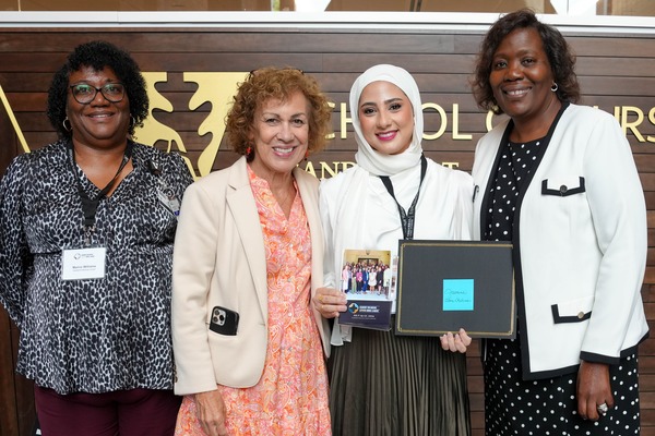 Four women pose, one holds a certificate signifying completion of a course