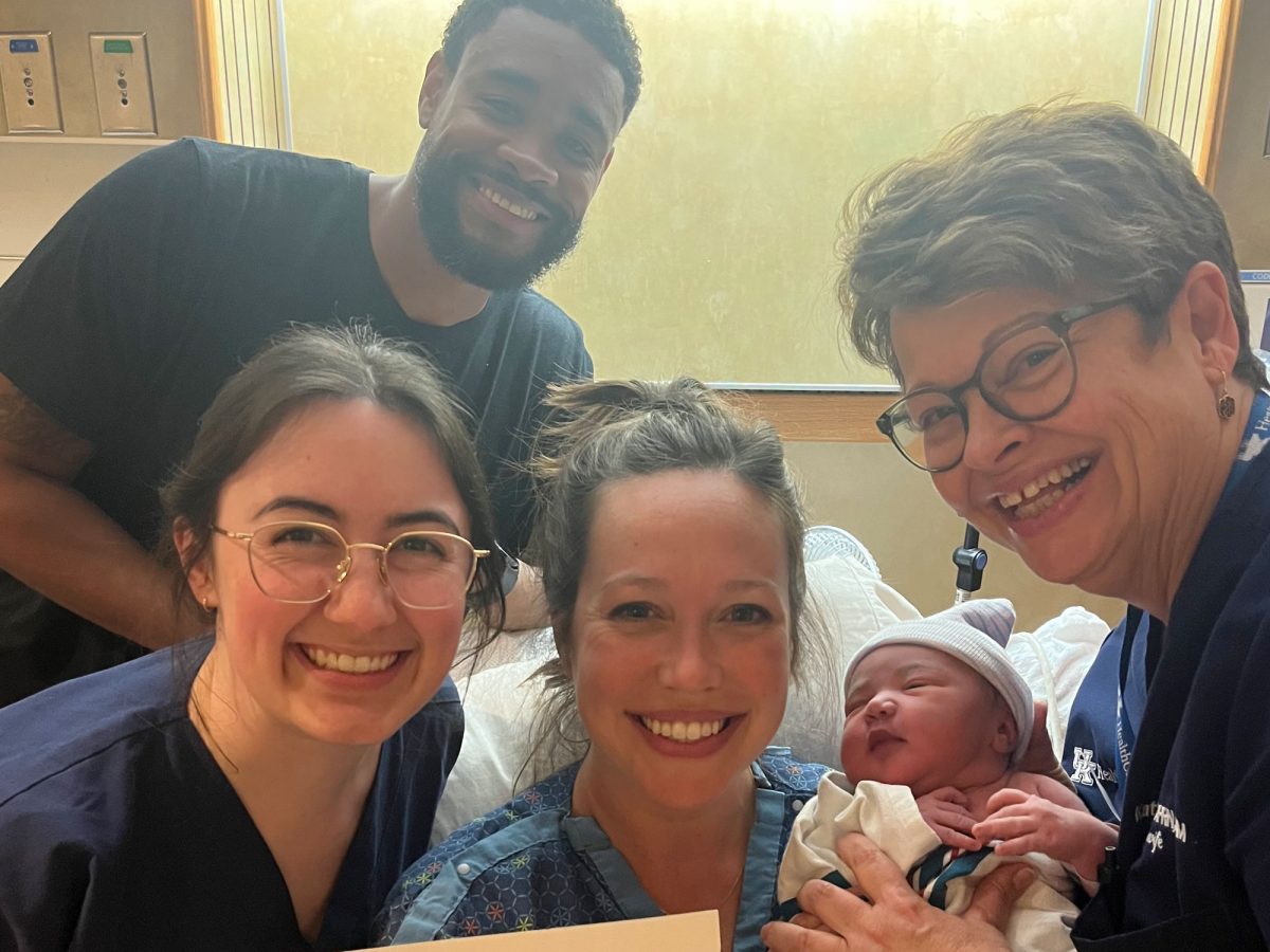 Nurse-Midwifes gather around a mother and baby